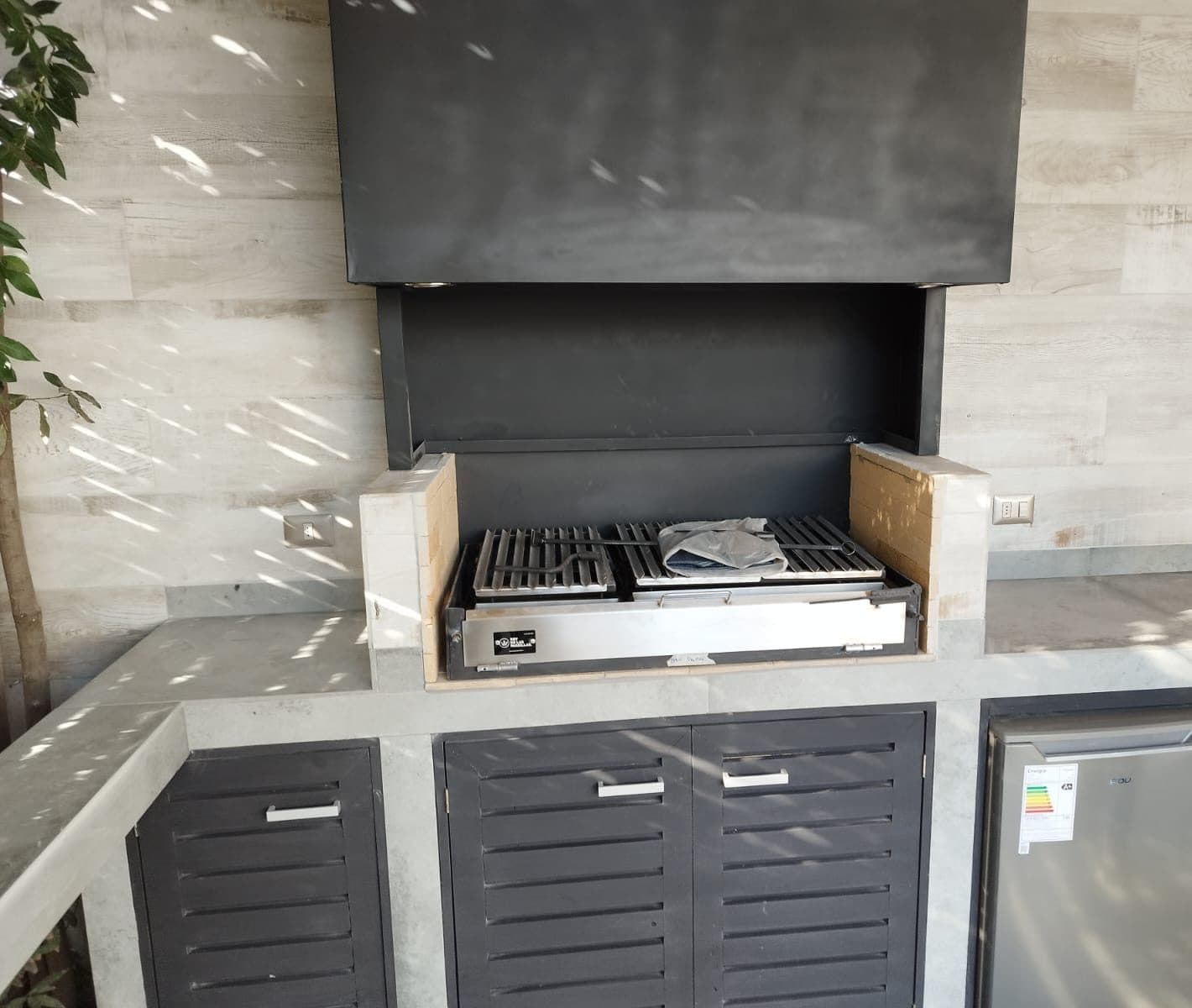 Parrilla de obra con campana metálica negra y encimera de hormigón