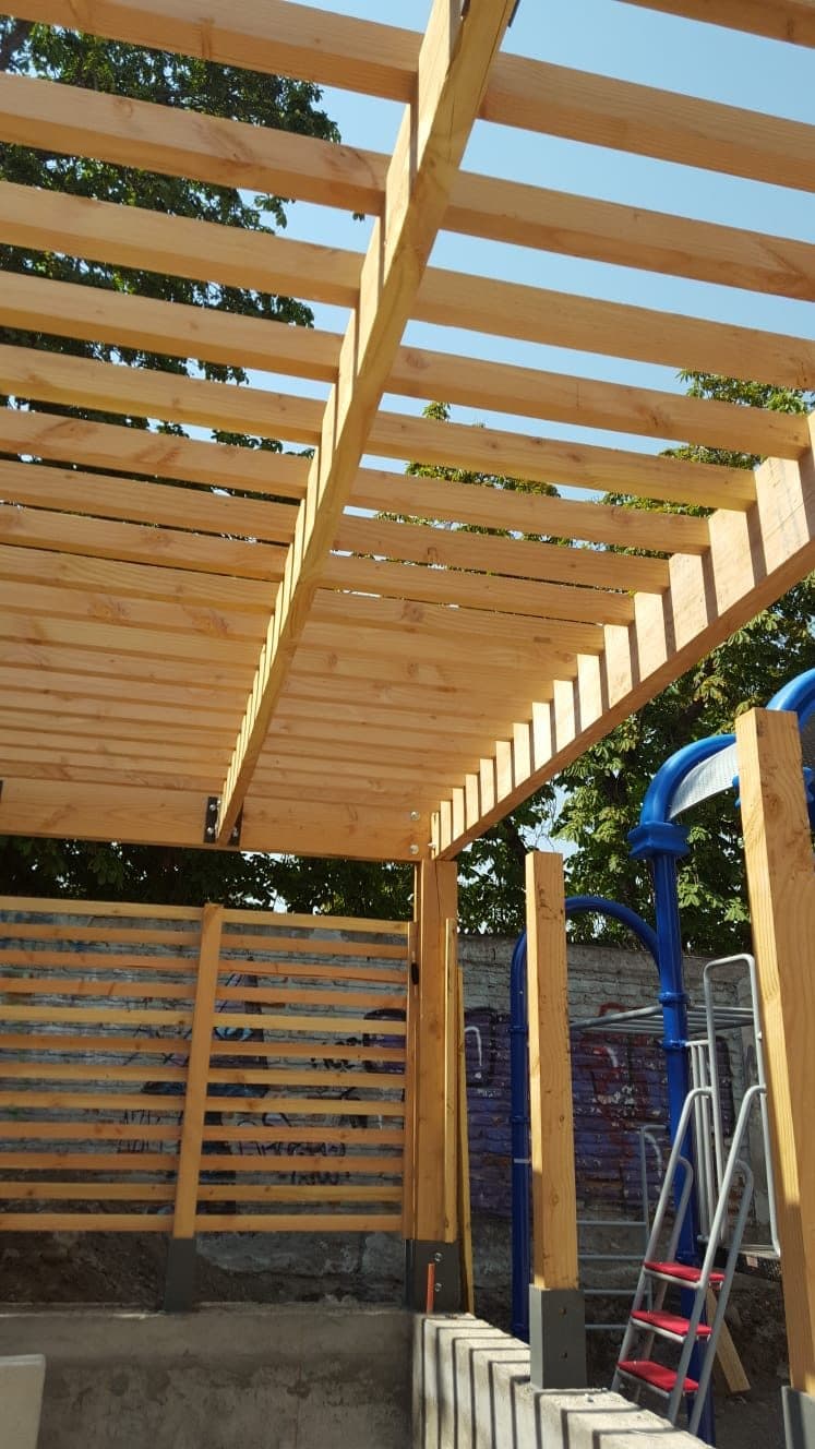Pérgola de madera recién terminada sobre un área de juegos infantiles