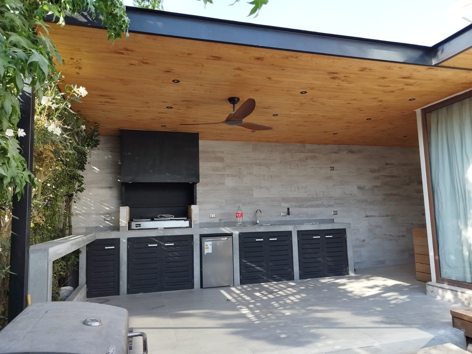 Quincho terminado con cielo de madera, mesón de hormigón y ventilador de techo